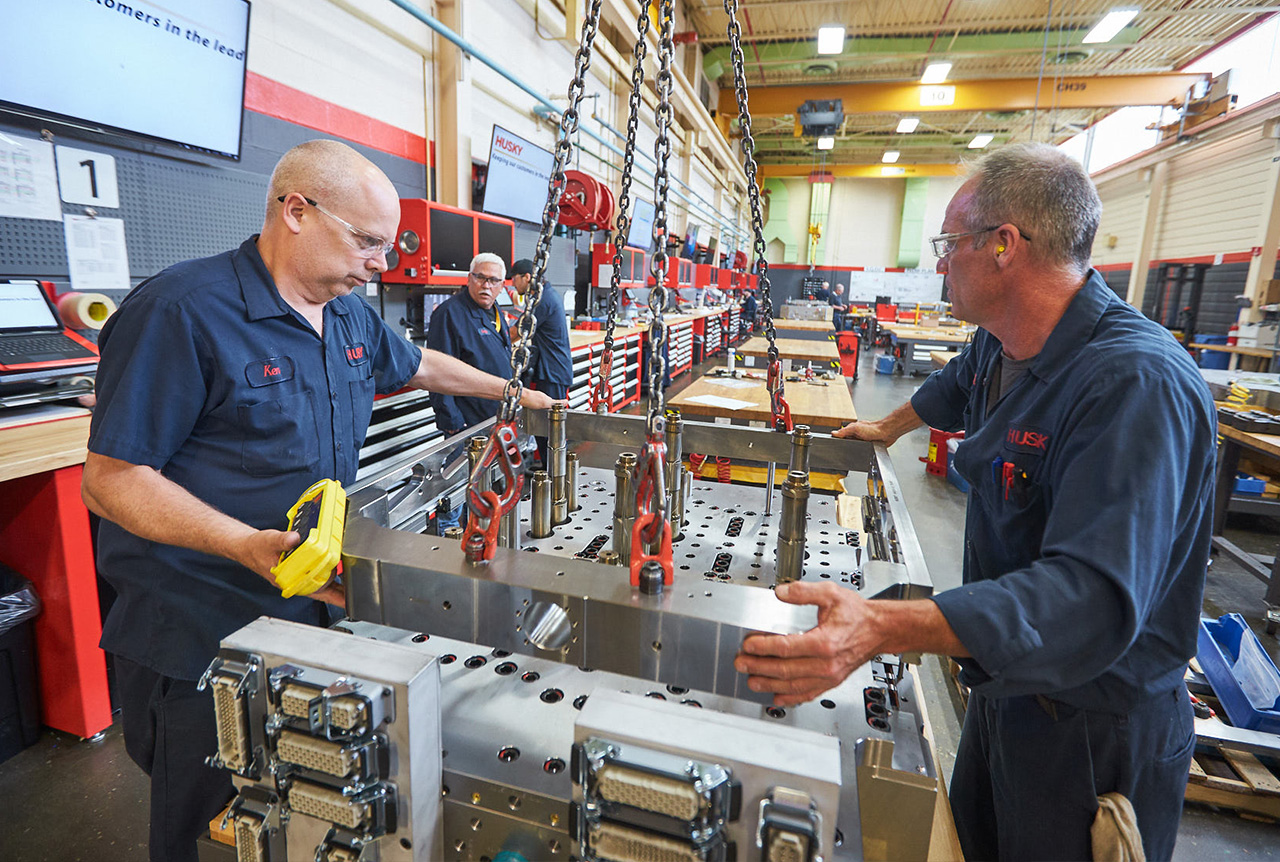 Husky technicians working on an injection molding system